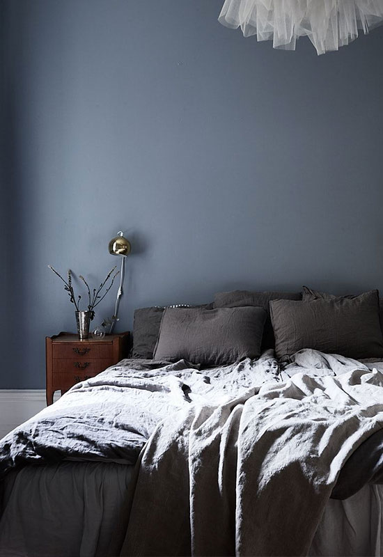 Mur bleu foncé et linge de lit gris anthracite