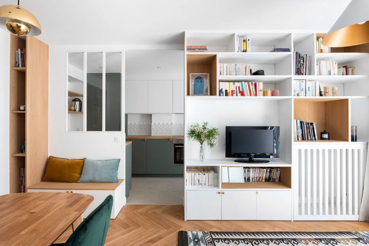 A la fois banquette, cache radiateur, étagères et modules de rangement, le mur est multifonctionnel