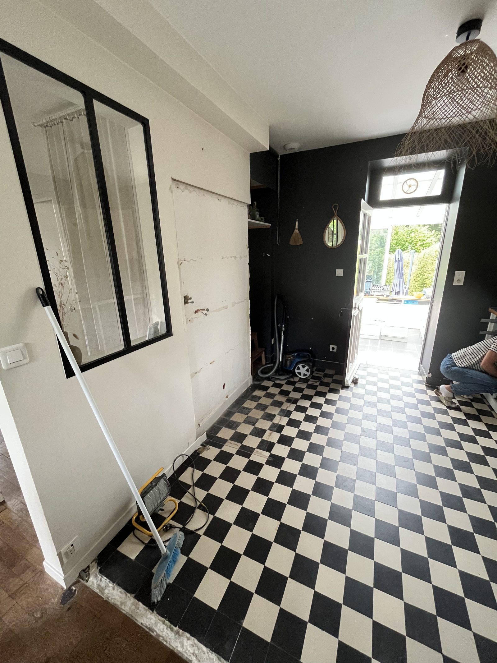 Cuisine avant rénovation : la pièce vidée avec carrelage en damier noir et blanc et murs sombres