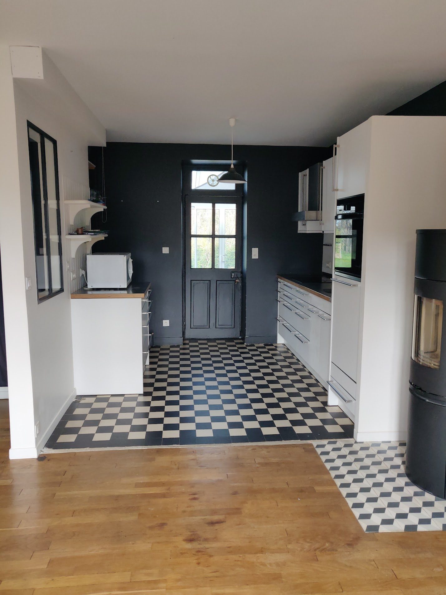 Cuisine avant rénovation : carrelage en damier noir et blanc et murs sombres de la cuisine d'origine