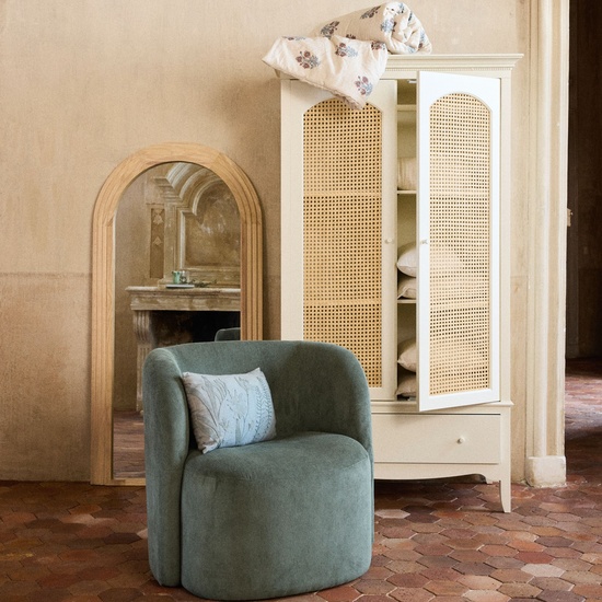 Armoire blanche en cannage Debbie dans une chambre boheme avec fauteuil vert