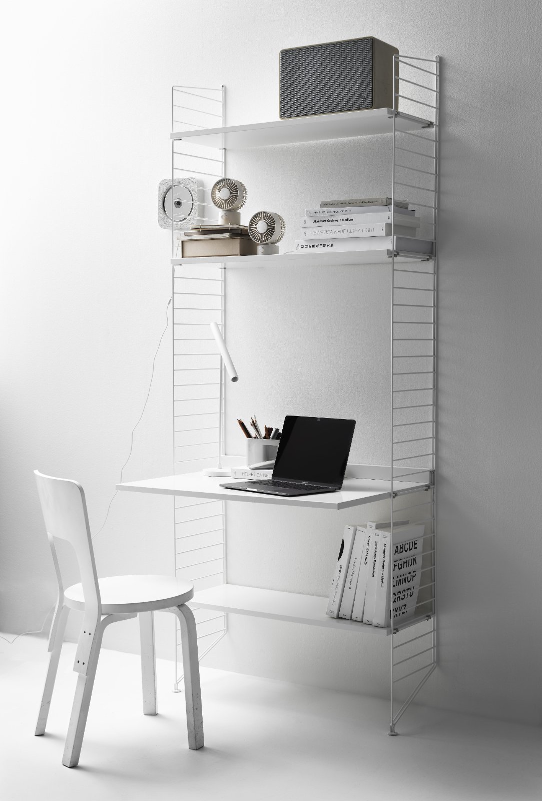 Bureau mural String installé dans une pièce avec chaise et objets de bureau