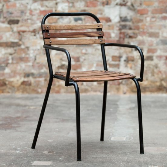 Chaise industrielle à accoudoirs en bois et métal noir devant un mur en briques