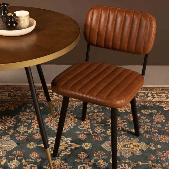 Chaise industrielle capitonnée en cuir cognac autour d'une table ronde en bois