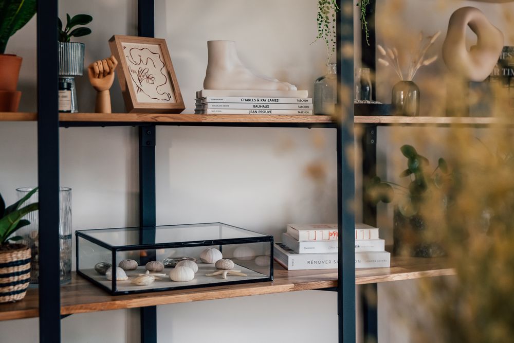 Étagère en métal noir avec objets en plâtre, main sculptée, livres Taschen et vase texturé