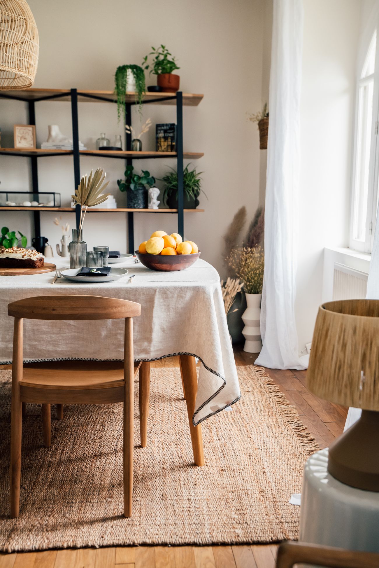 Vue d'ensemble de la salle à manger avec étagère en métal noir, table dressée pour un brunch et tapis en jute
