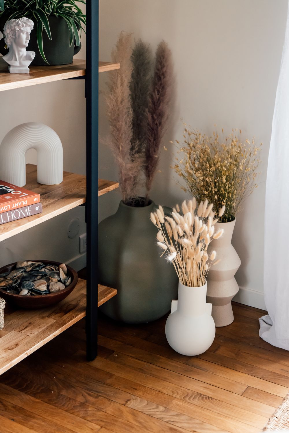 Étagère en bois clair avec buste en plâtre, vase en céramique verte et pampas séchées