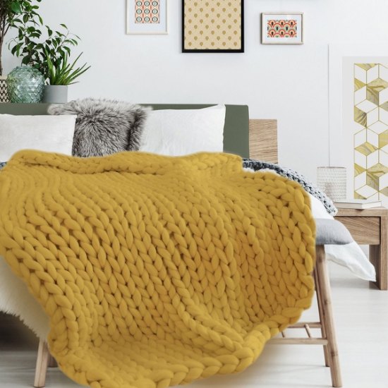 Plaid grosse maille ocre Chunky posé sur un lit en chambre cocooning