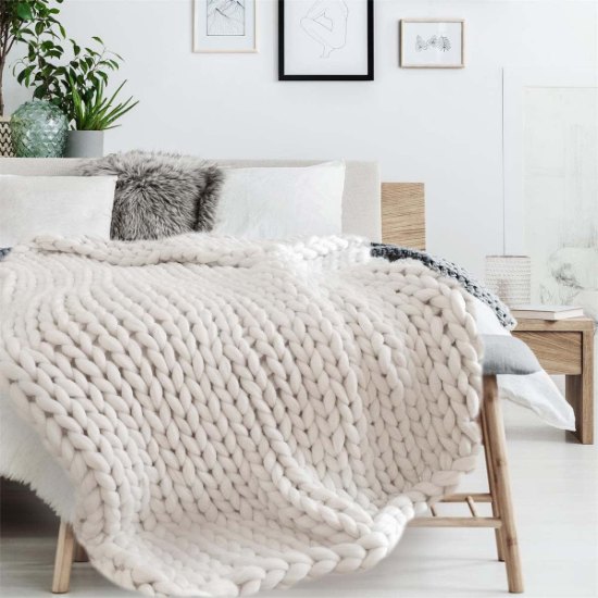 Plaid grosse maille blanc posé sur un lit dans une chambre cosy