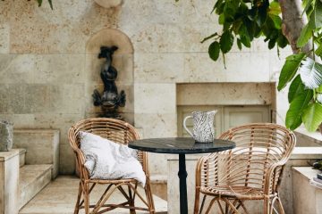 Table de bistrot en marbre noir et deux fauteuils en rotin dans un patio mediterraneen