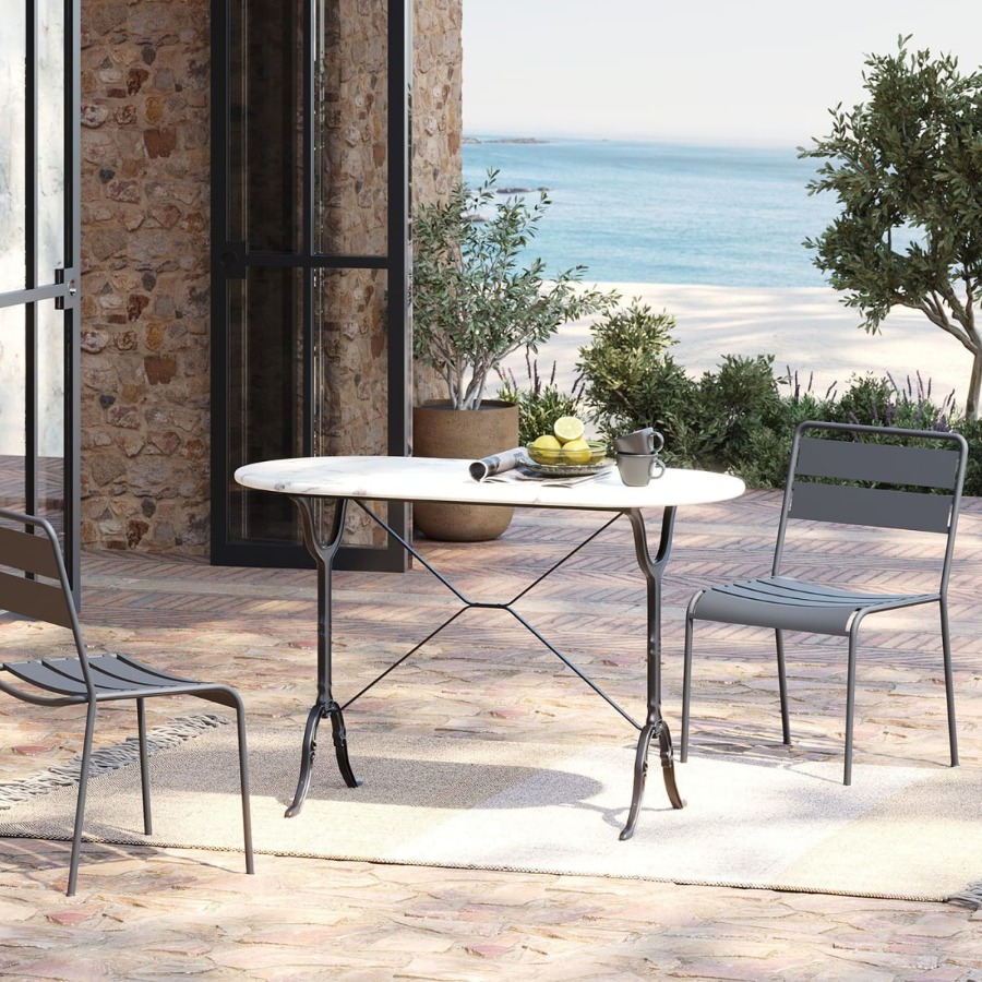 Table de bistrot ovale en marbre blanc installee sur une terrasse en bord de mer