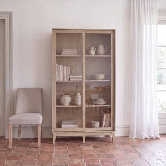 Buffet vitrine vintage Illa en bois clair dans un salon lumineux