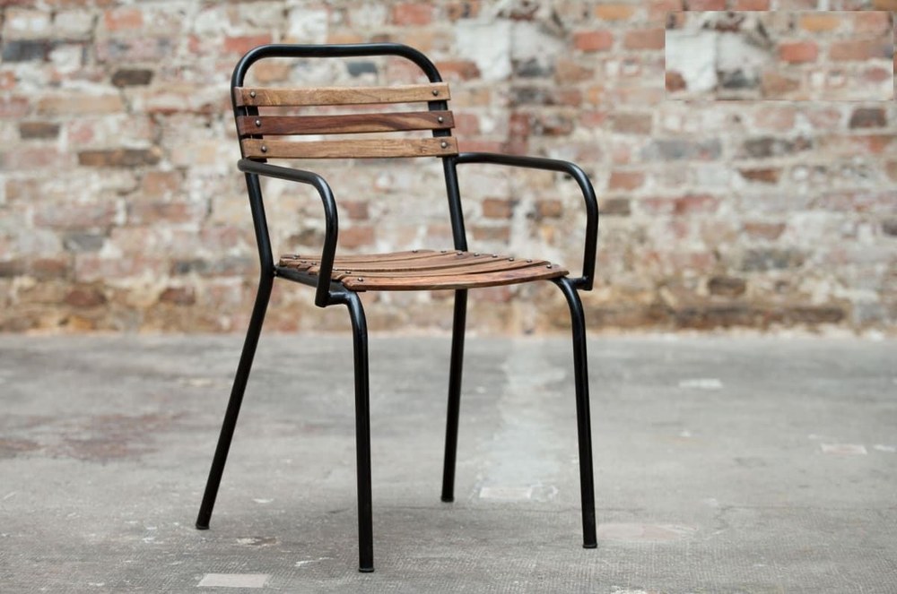 Chaise industrielle Mistral en bois et métal noir installée devant un mur en briques
