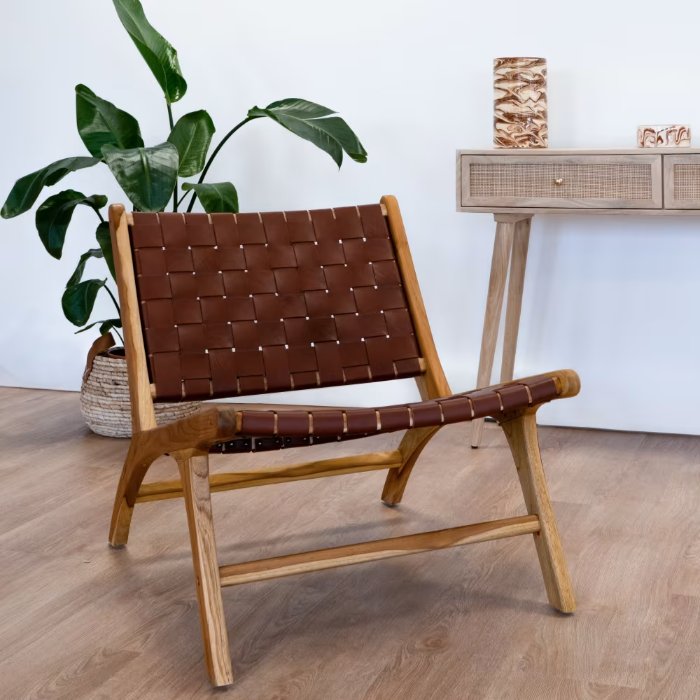 Fauteuil en teck et cuir tressé marron Kuna dans un salon avec plante et console
