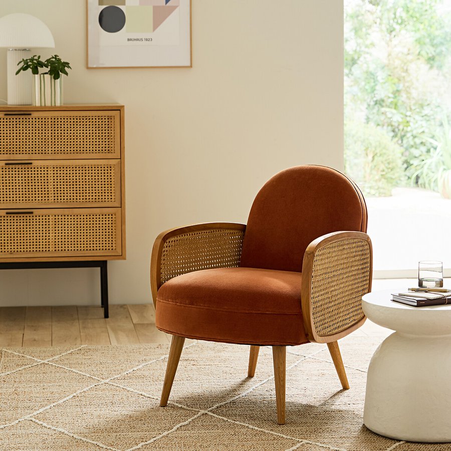 Fauteuil vintage en velours orange cuit et cannage dans un salon au charme rétro