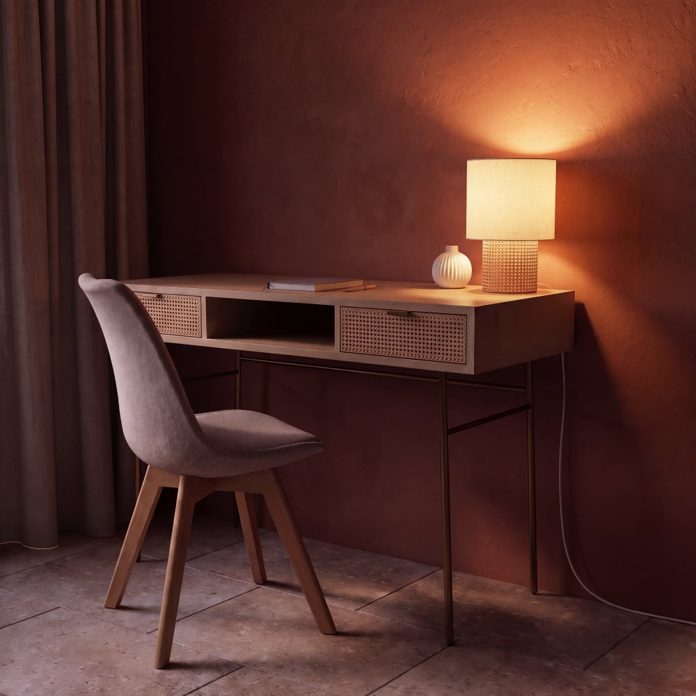 Lampe en rotin tressé et abat-jour beige KARVEN allumée sur un bureau