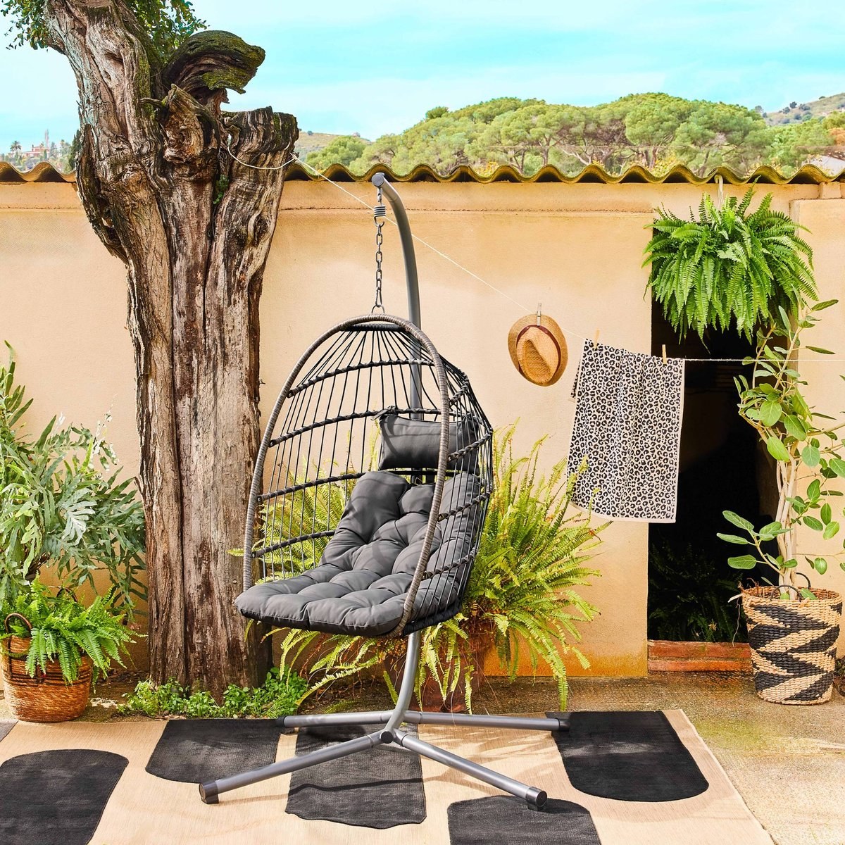 Fauteuil suspendu en rotin SWEEEK Toscana installé en extérieur dans un patio méditerranéen