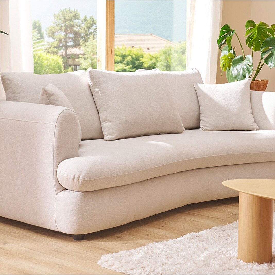 Canapé arrondi convertible Sacha en velours texturé beige, en situation dans un salon lumineux