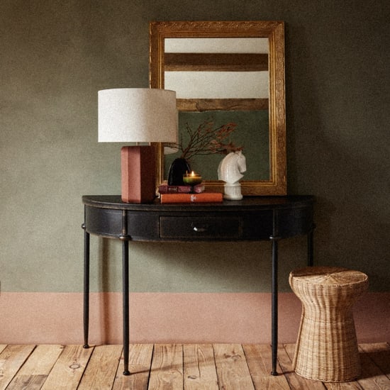 Console d'entrée Alienor demi-lune en fer forgé noir devant un mur kaki