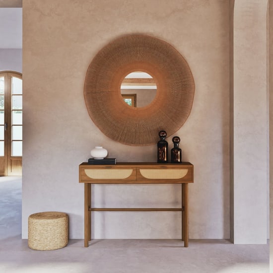 Console d'entrée Tarifa en rotin tressé sous un grand miroir en fibres naturelles