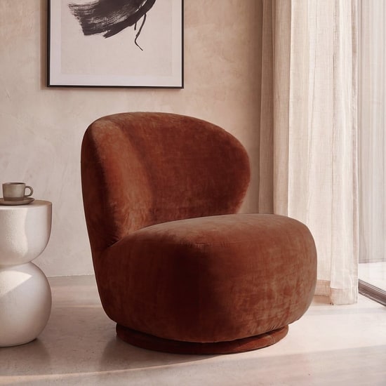 Fauteuil pivotant en velours auburn Maisons du Monde près d'un rideau en lin