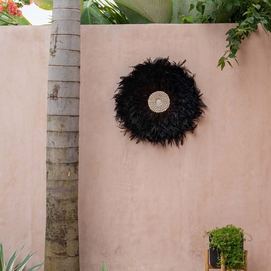 Juju hat COASTAL JUJU en plumes noires accroche sur un mur de patio rose