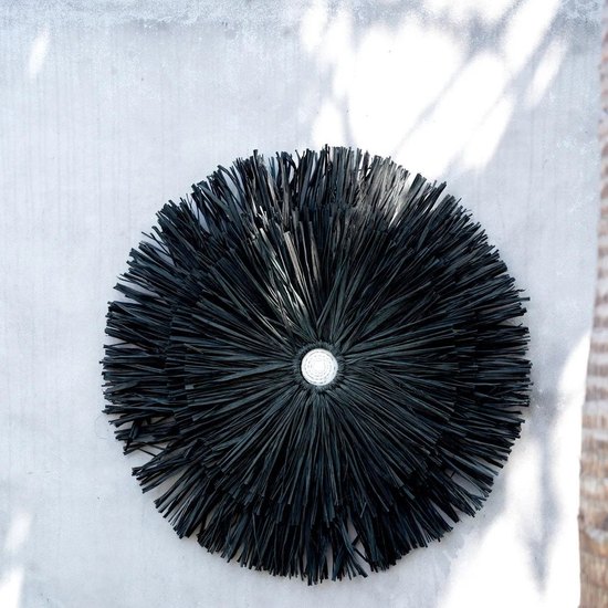 Juju hat JUJU en raphia noir accroche sur un mur blanc chaule