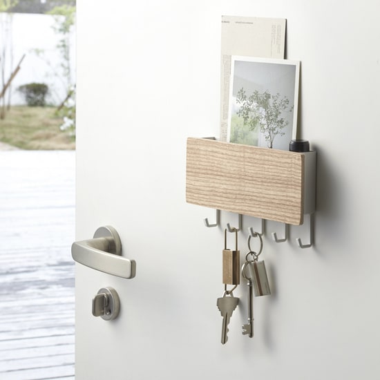 Porte-clés mural Rin en bois clair fixé sur une porte avec ses clés et des cartes postales